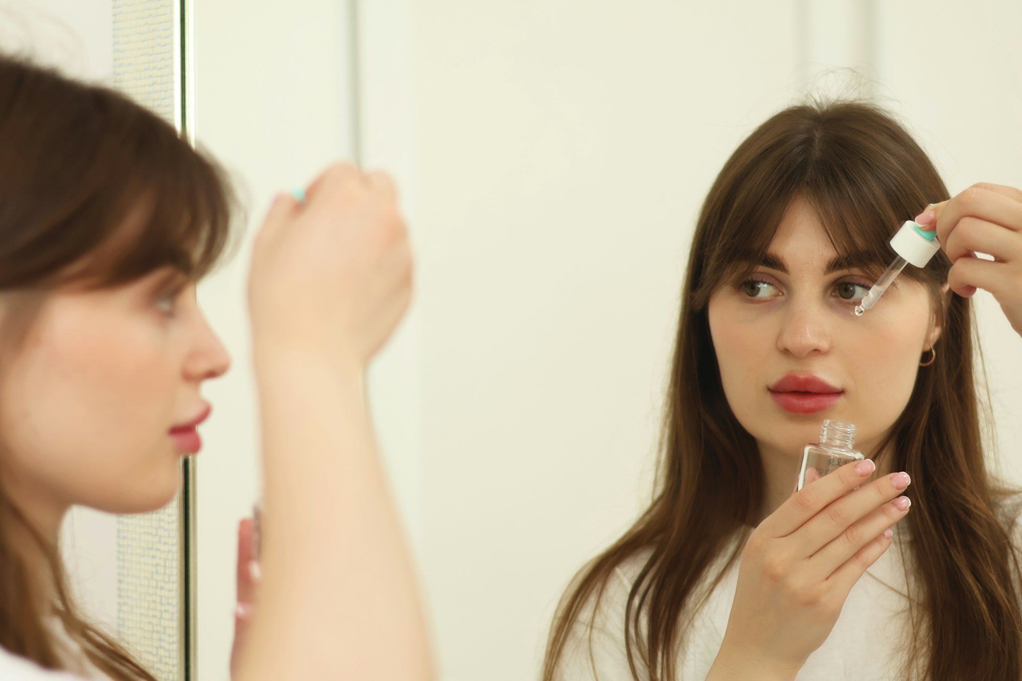 Une femme s'observe dans un miroir : suivre l'évolution de la tache rouge dans l'œil pendant quelques jours suffit, elle disparaît seule.