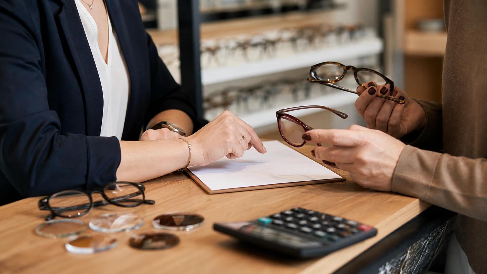 Un opticien détaille le prix et le remboursement de lunettes avec une cliente en magasin.
