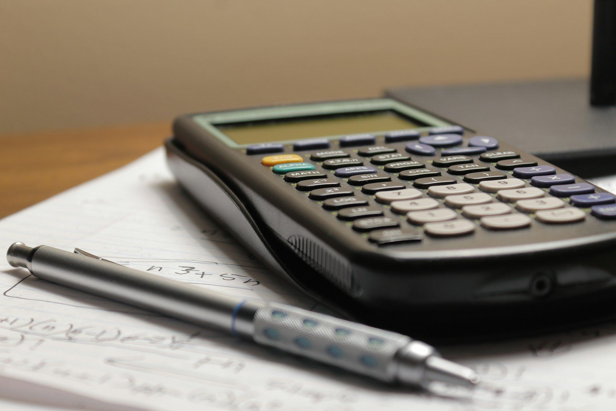 Calculatrice et stylo posés sur un document de prévisionnel, préparation du business plan d'un magasin d'optique