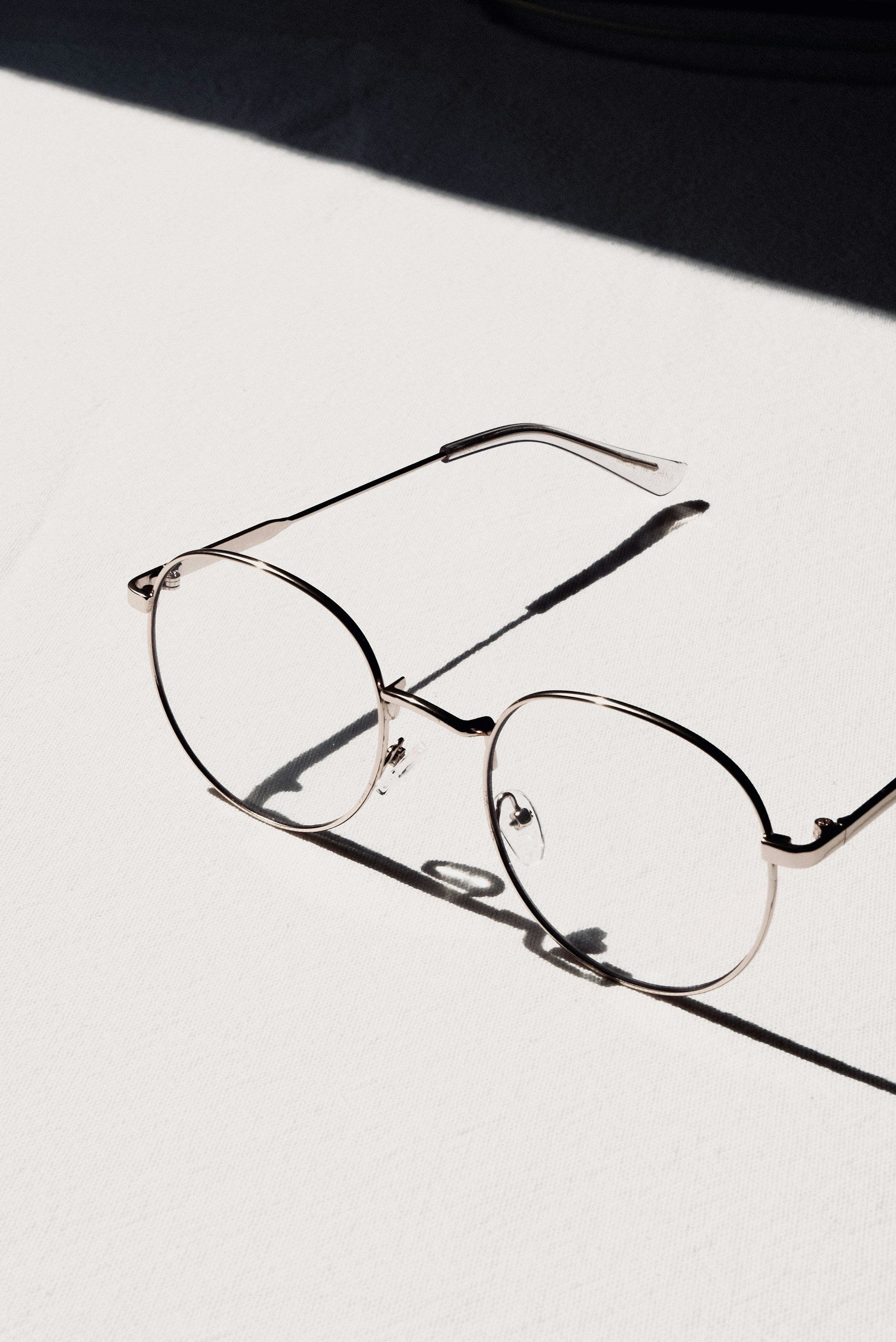 Lunettes à monture argentée posées sur une table blanche, évoquant le coût d'un équipement et le budget d'un recrutement en alternance.