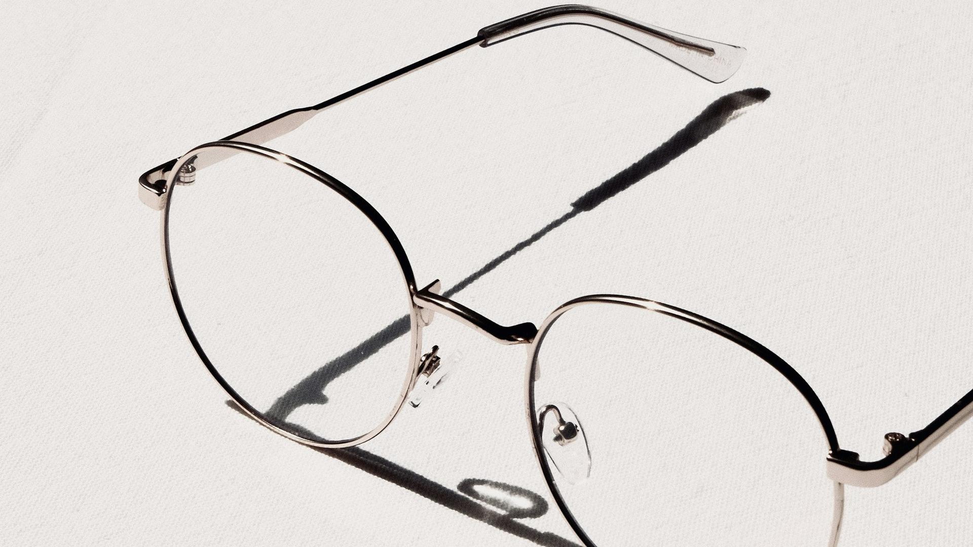 Lunettes à monture argentée posées sur une table blanche, évoquant le coût d'un équipement et le budget d'un recrutement en alternance.