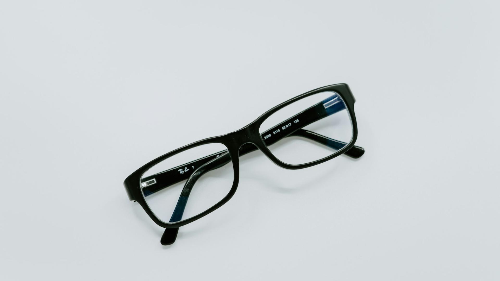 Lunettes à monture noire posées sur une surface claire, le budget d'une consultation pour un œil qui saute
