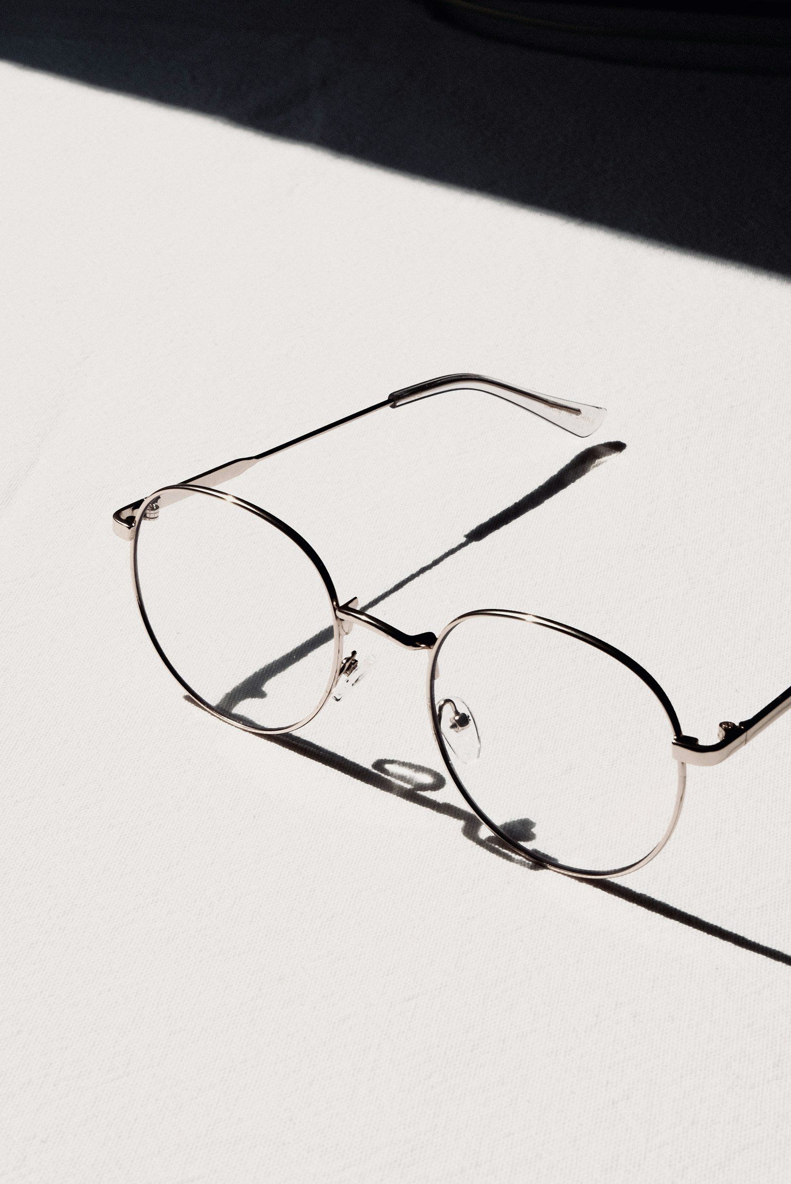 Lunettes à monture argentée posées sur une table blanche, gros plan sur le verre et la branche