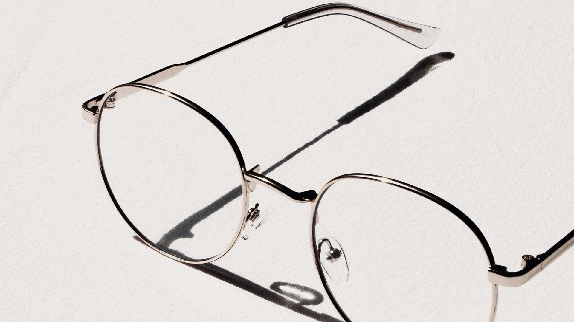 Lunettes à monture argentée posées sur une table blanche, gros plan sur le verre et la branche