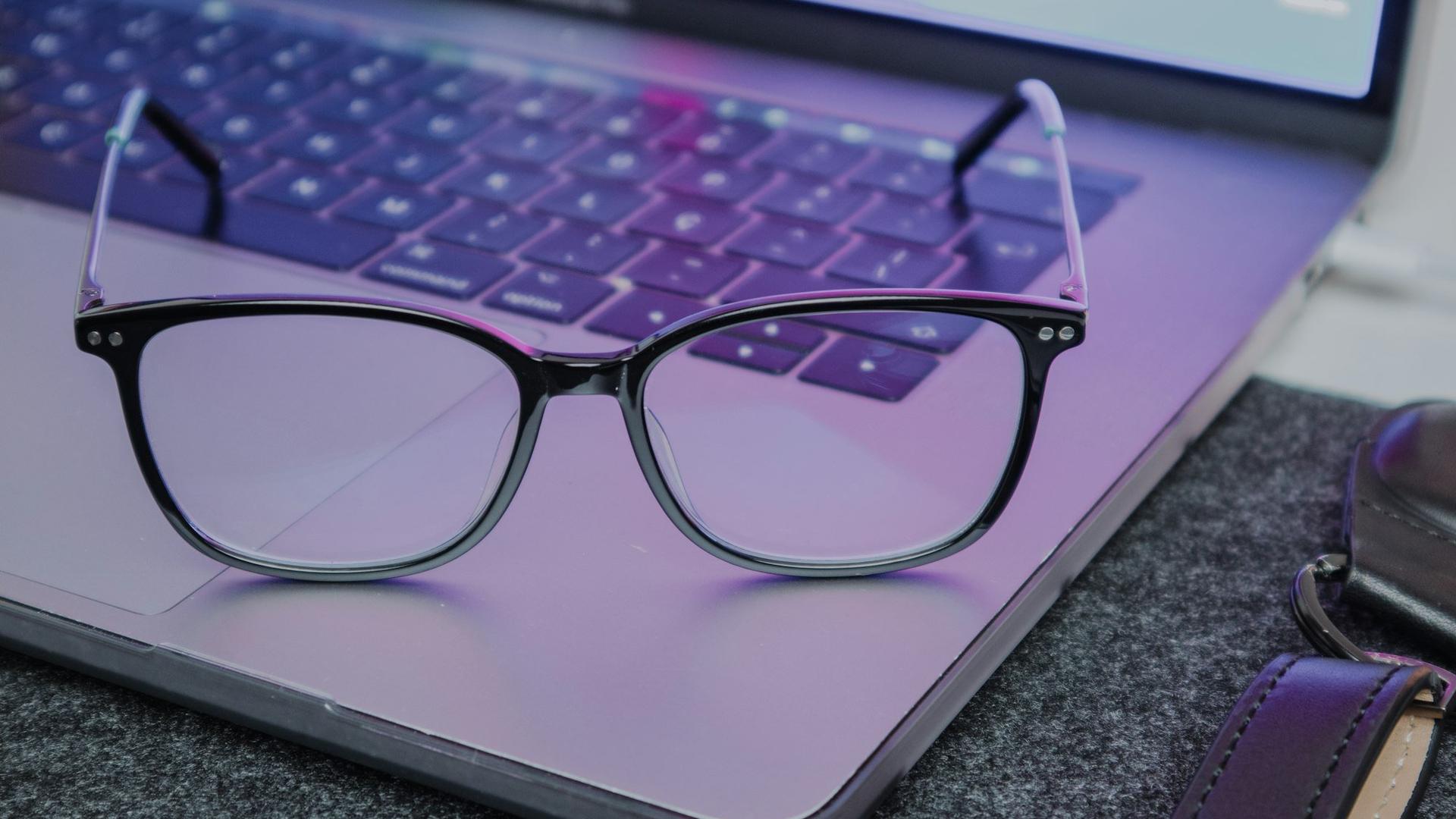 Lunettes posées sur un ordinateur portable, le lien entre lunettes connectées et lumière bleue des écrans