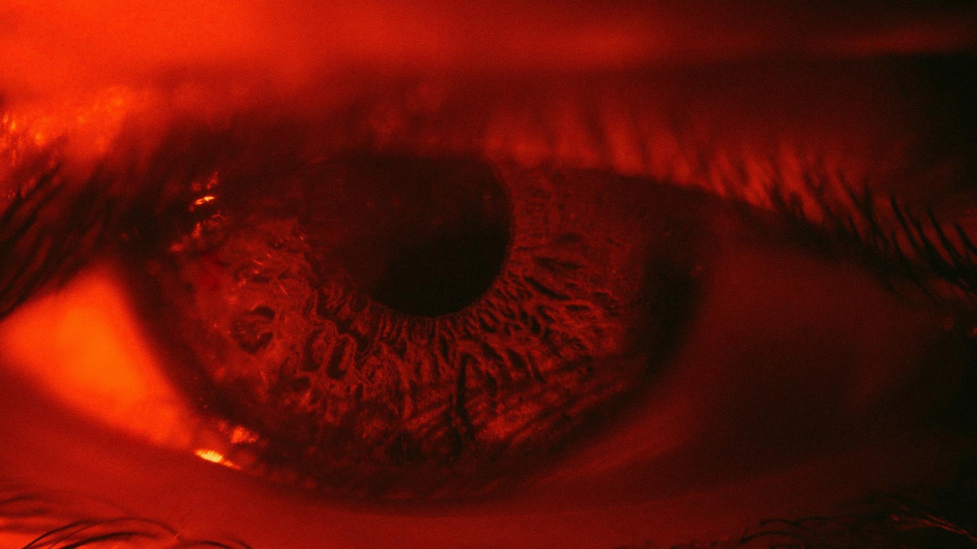 Gros plan sur un œil humain éclairé d'une lumière rouge, illustration de la rougeur oculaire