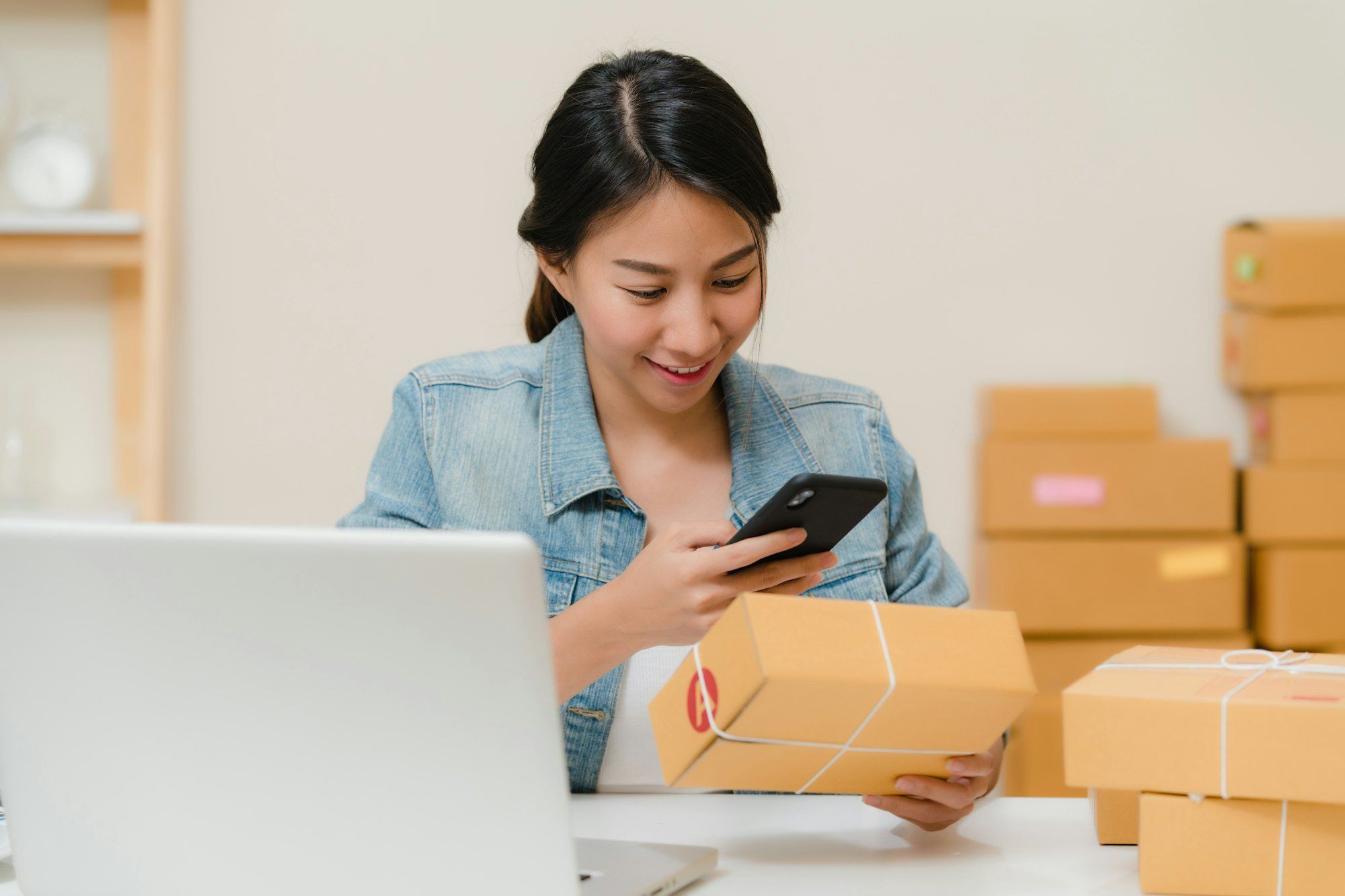 Professionnelle vérifiant une commande en ligne entre ordinateur et cartons, gestion d'une boutique e-commerce