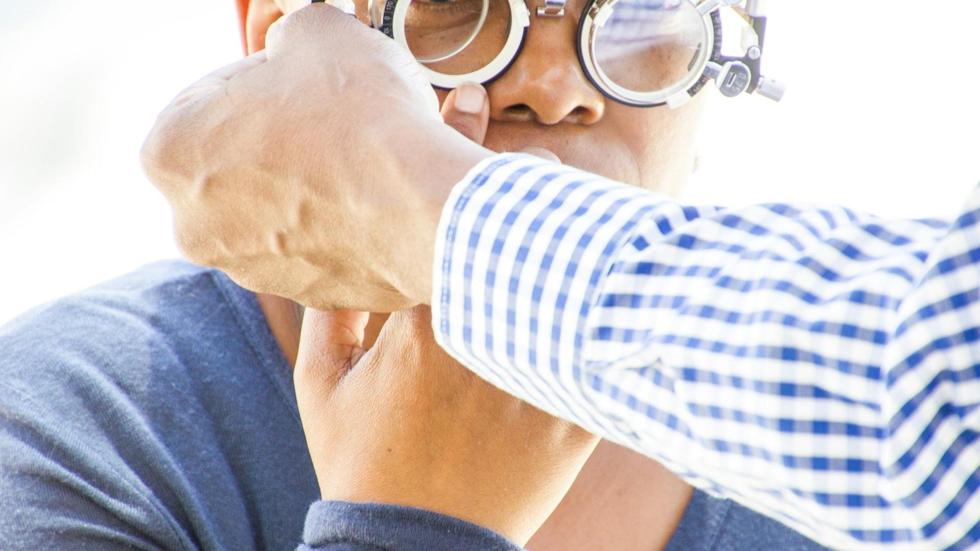 Jeune personne portant des lunettes loupes, en train d'examiner du matériel, illustrant la formation d'un alternant en optique.