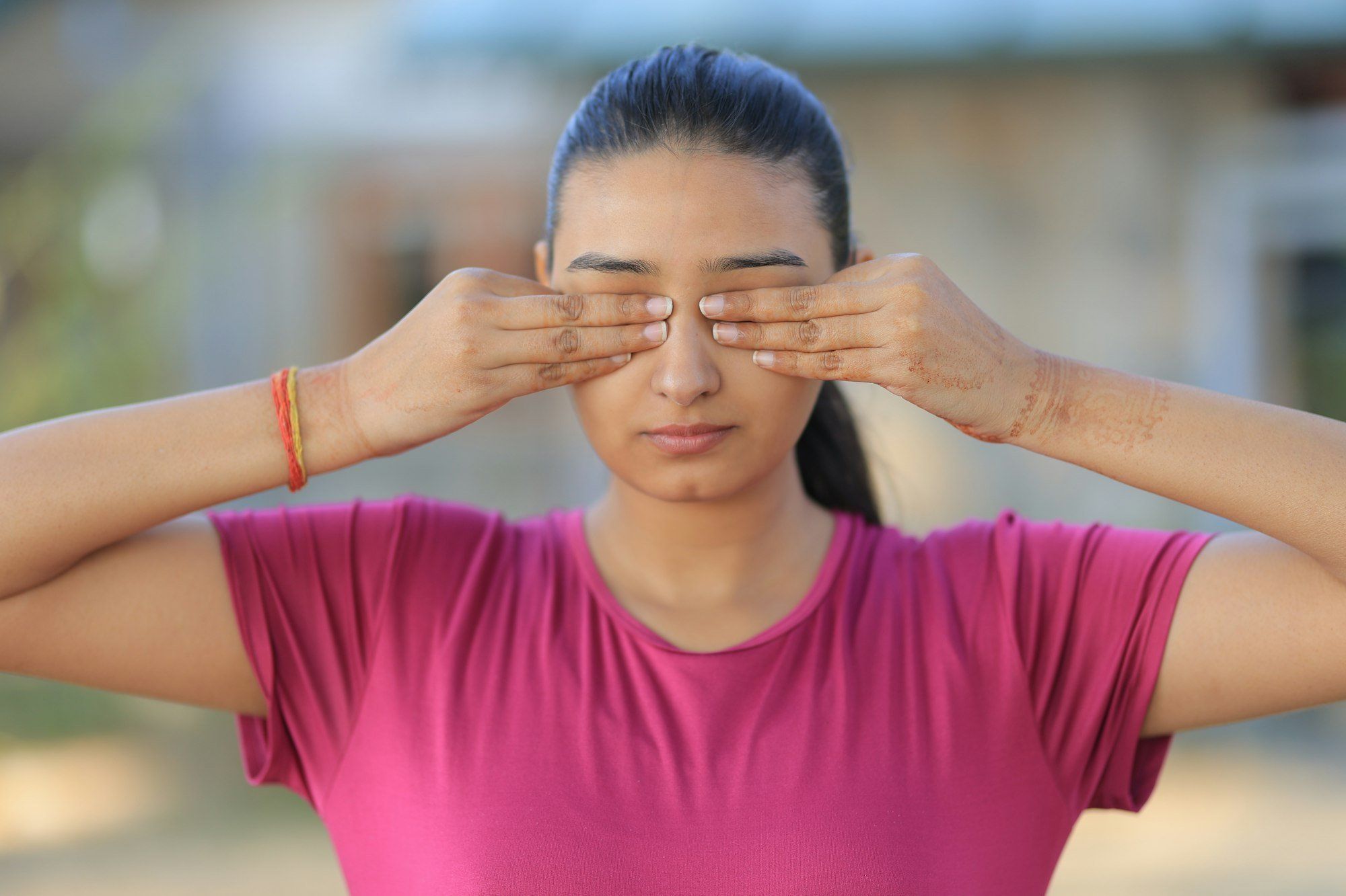 Une jeune femme couvre ses yeux avec ses mains : se frotter ou se presser les yeux peut faire éclater un petit vaisseau sous la conjonctive.