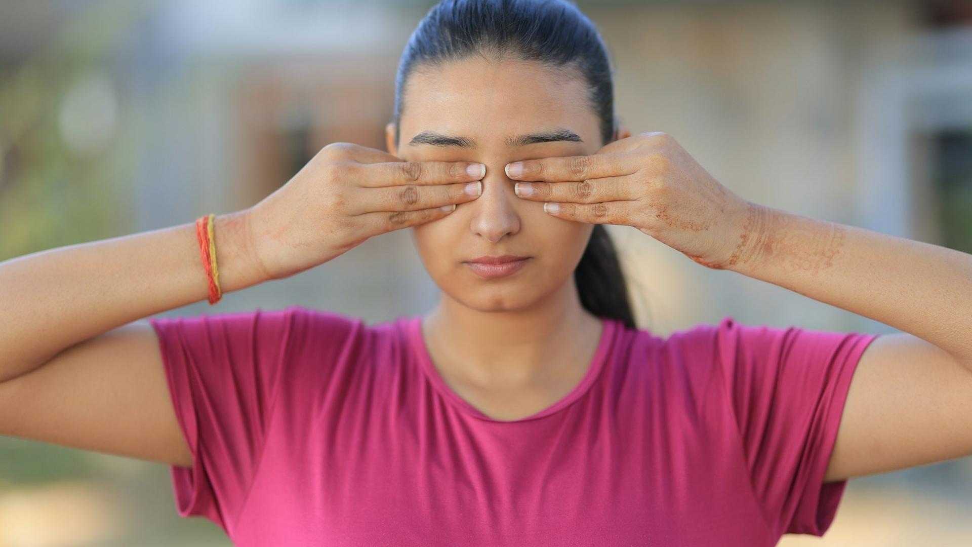 Une jeune femme couvre ses yeux avec ses mains : se frotter ou se presser les yeux peut faire éclater un petit vaisseau sous la conjonctive.