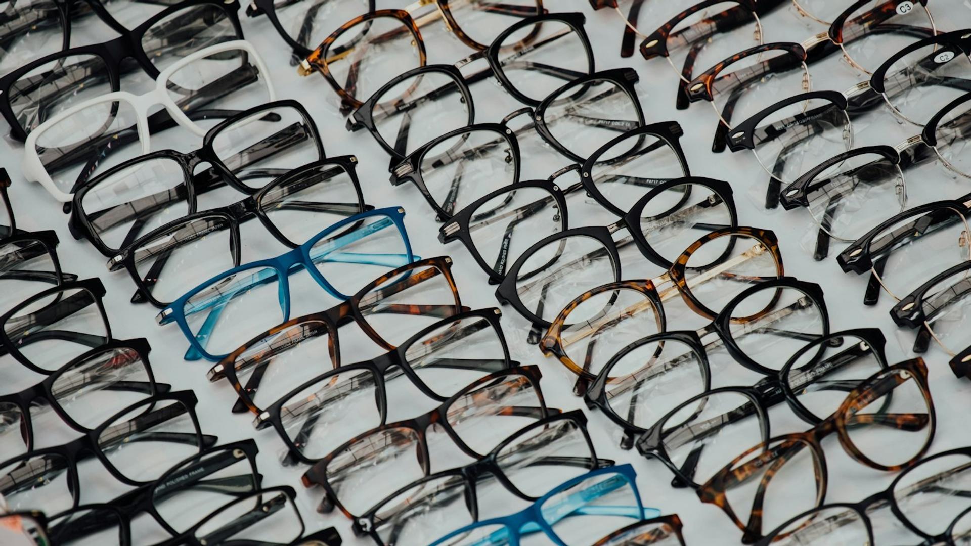 Grande quantité de lunettes de vue et de solaires disposées en rangées, illustrant le stock nécessaire pour absorber un pic d'activité en optique