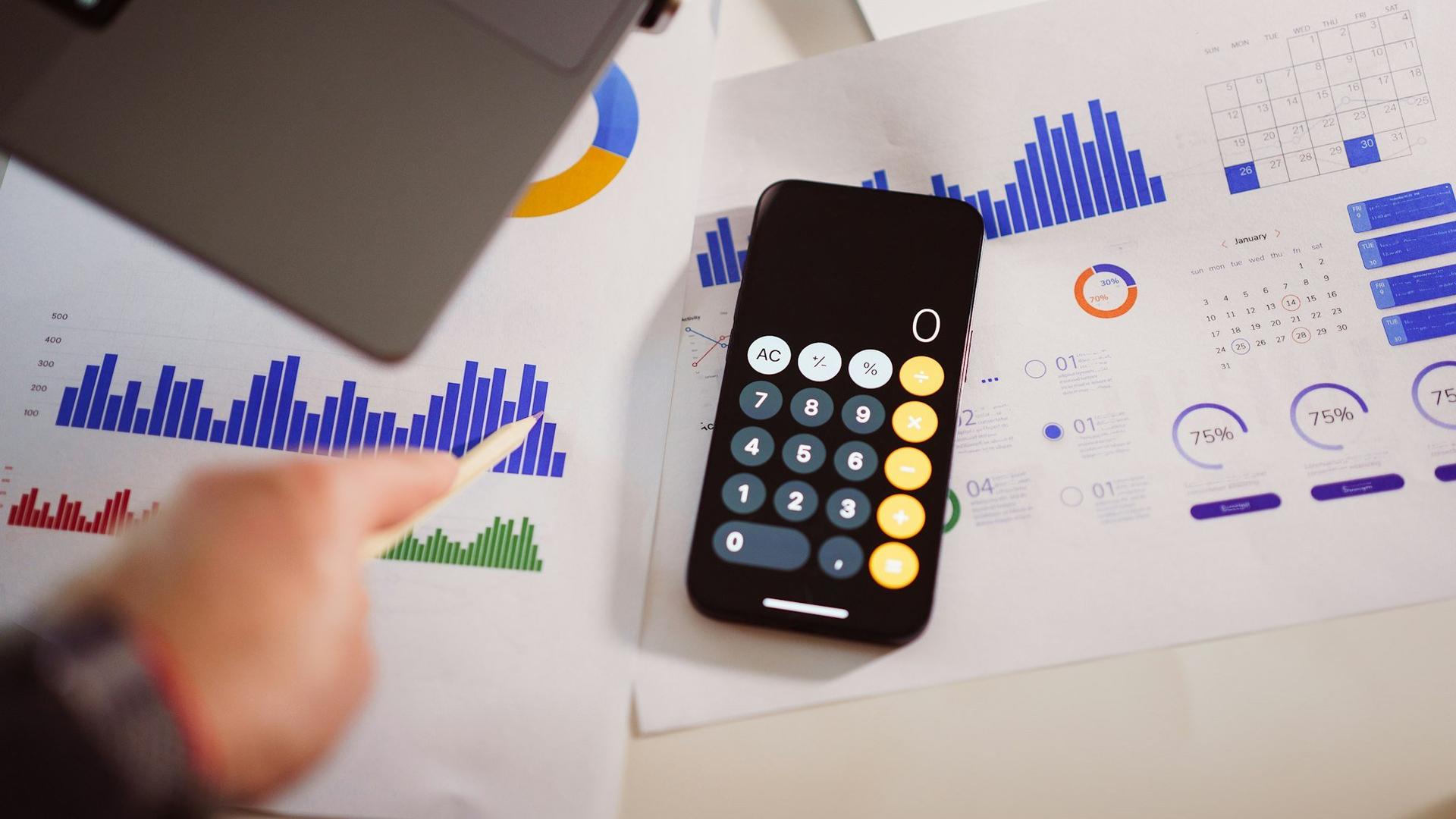 Calculatrice posée sur des documents financiers et graphiques, pour le calcul du budget publicitaire