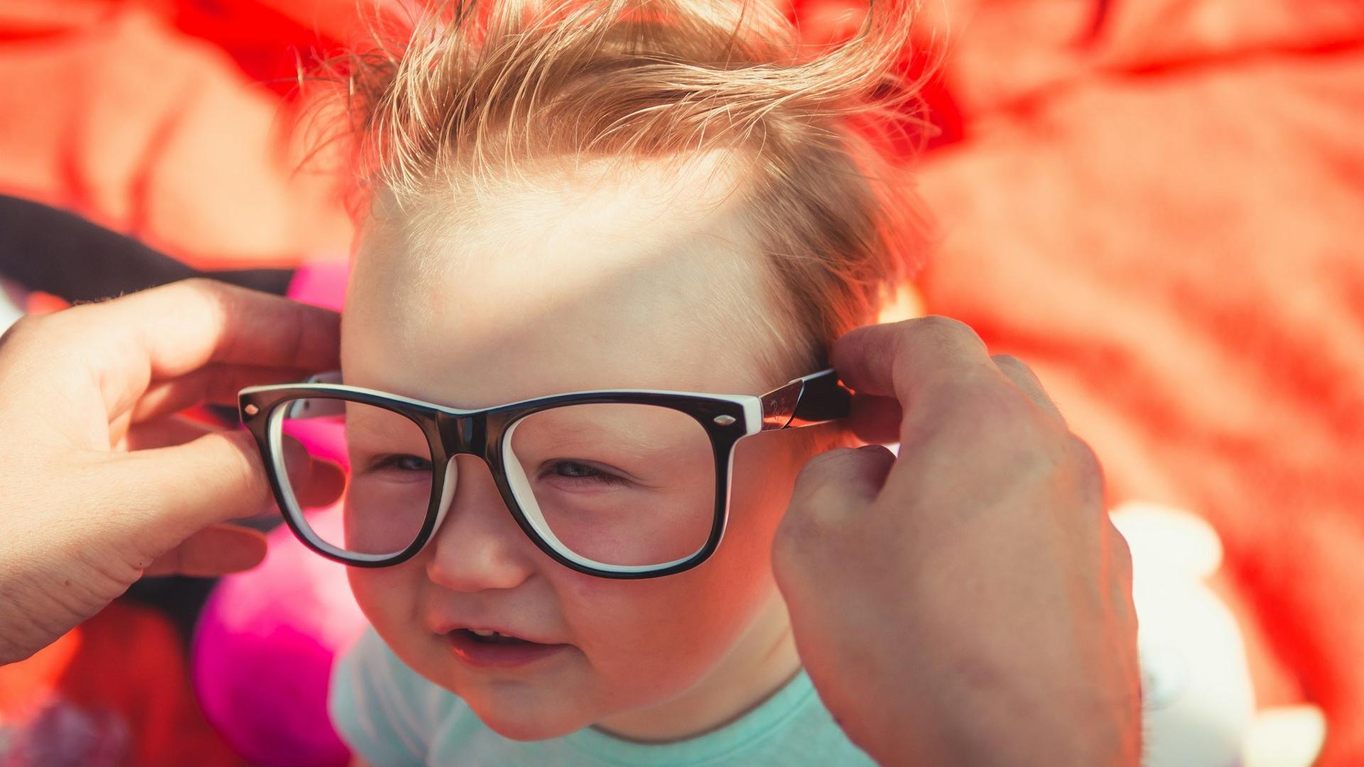 Jeune enfant portant des lunettes à monture noire, les symptômes de l'amblyopie étant souvent repérés lors de l'adaptation d'une première correction