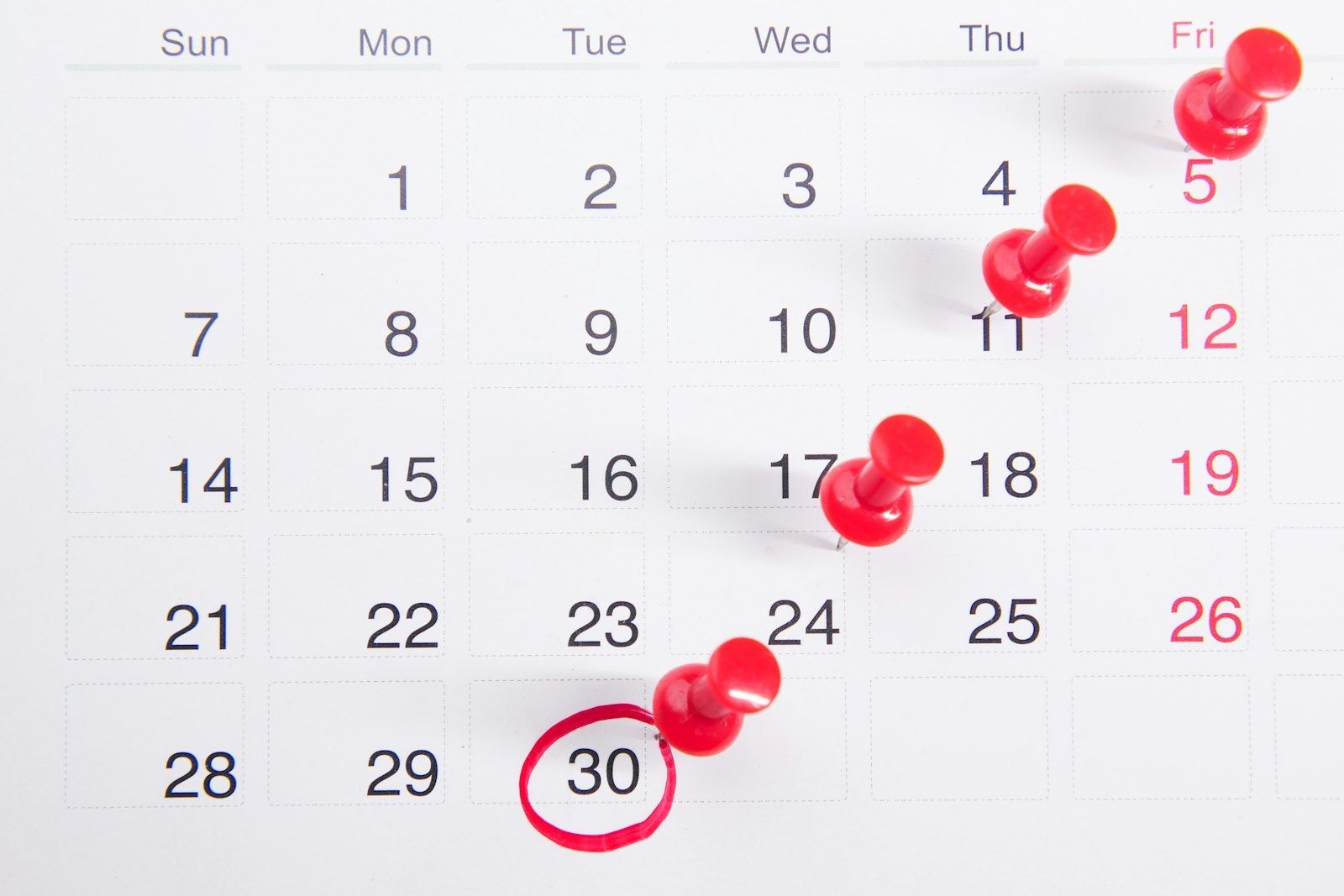 Calendrier mural avec des punaises rouges sur des dates clés, symbolisant la planification des rendez-vous et de l'équipe avant un pic