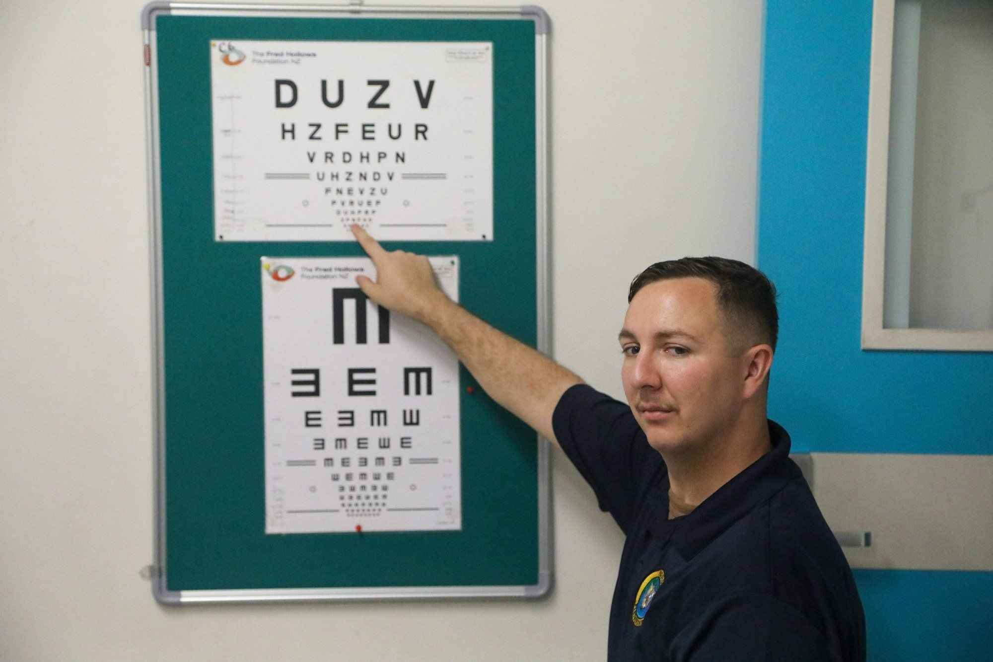Patient désignant un tableau de lettres lors d'un examen de la vue, pour vérifier l'origine d'un spasme de la paupière