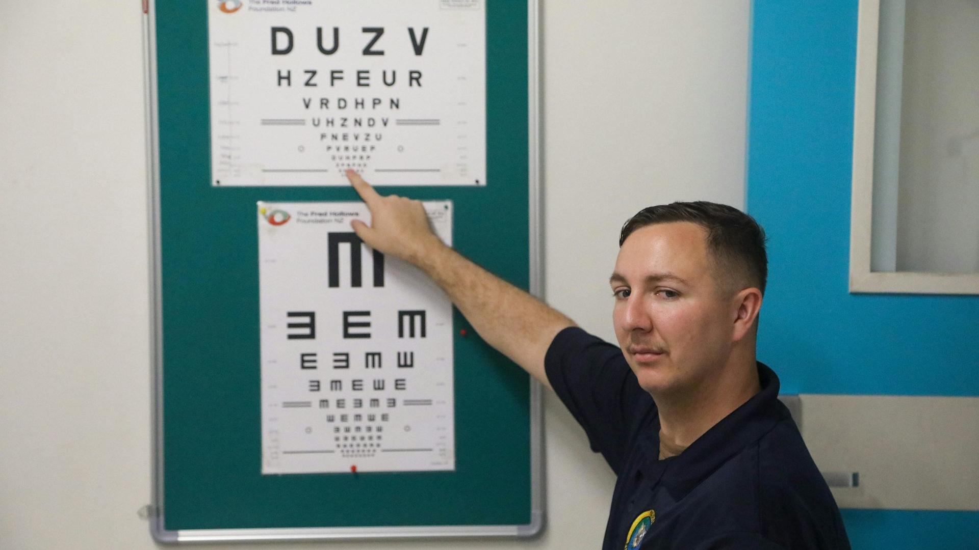 Patient désignant un tableau de lettres lors d'un examen de la vue, pour vérifier l'origine d'un spasme de la paupière