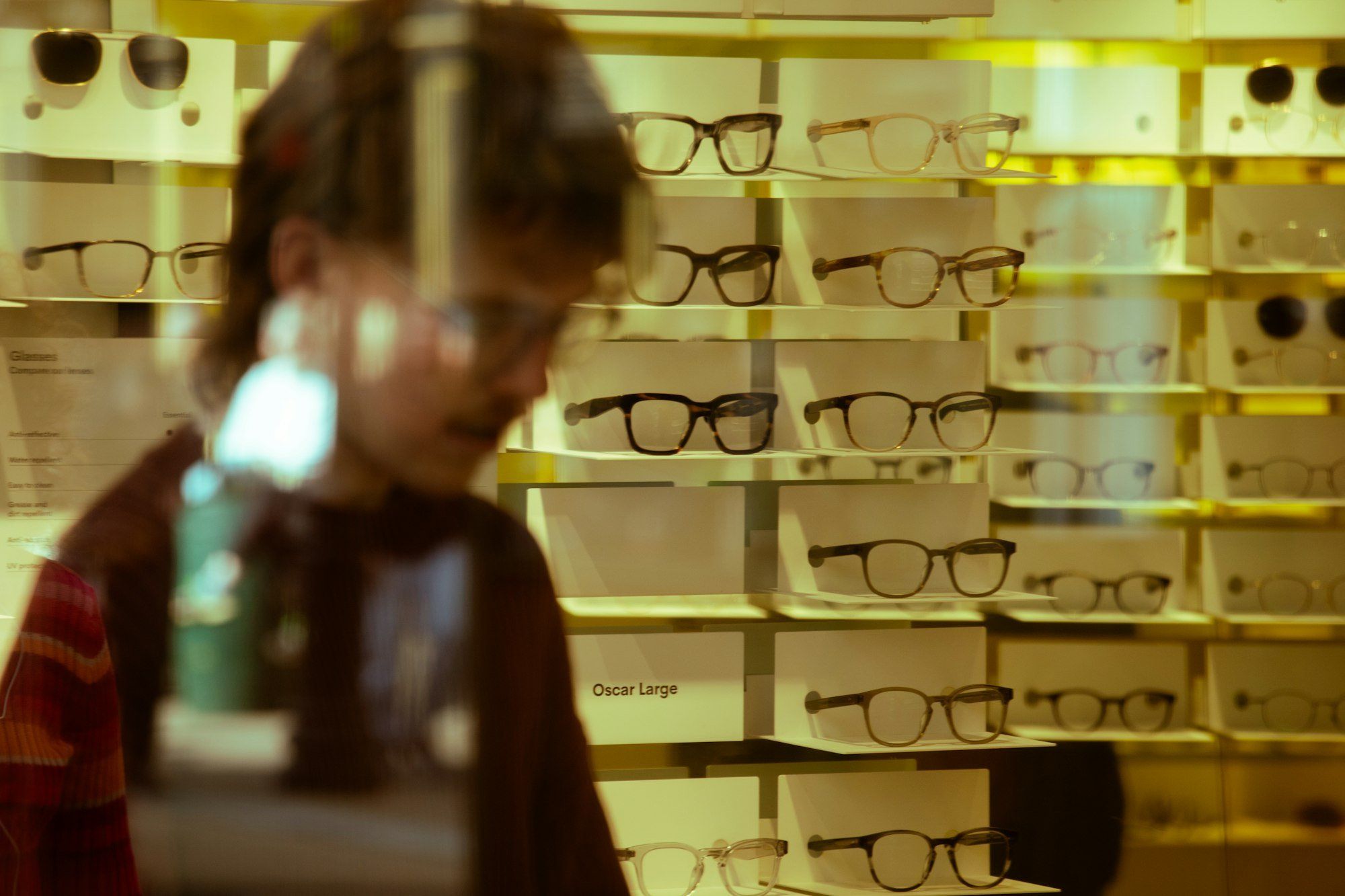 Client en train de choisir des lunettes dans une boutique d'optique, illustrant l'enjeu de recruter et de vendre pour financer une bonne équipe