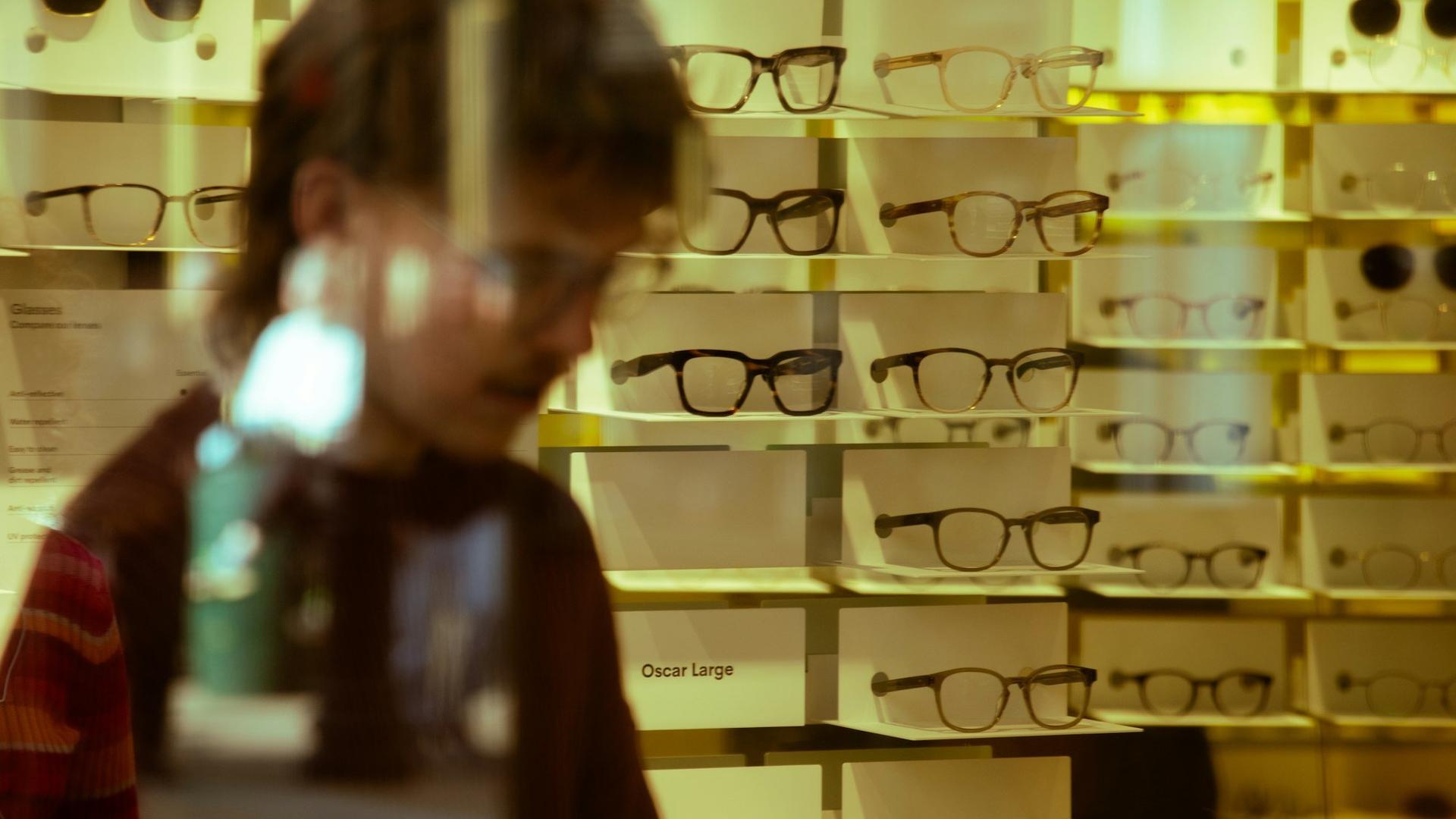 Client en train de choisir des lunettes dans une boutique d'optique, illustrant l'enjeu de recruter et de vendre pour financer une bonne équipe