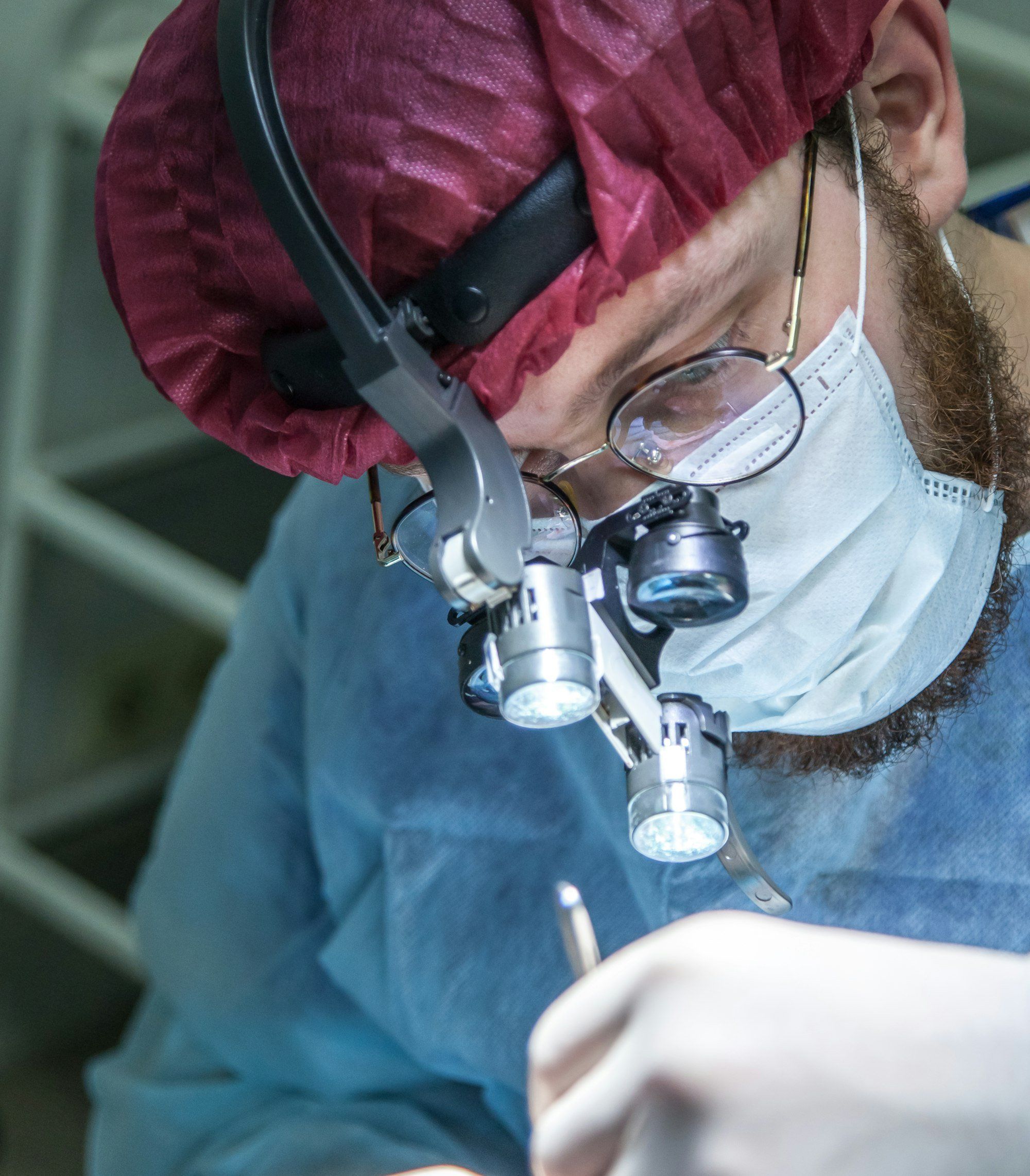 Chirurgien portant des loupes opératoires avec éclairage, la chirurgie étant le traitement de référence du ptosis