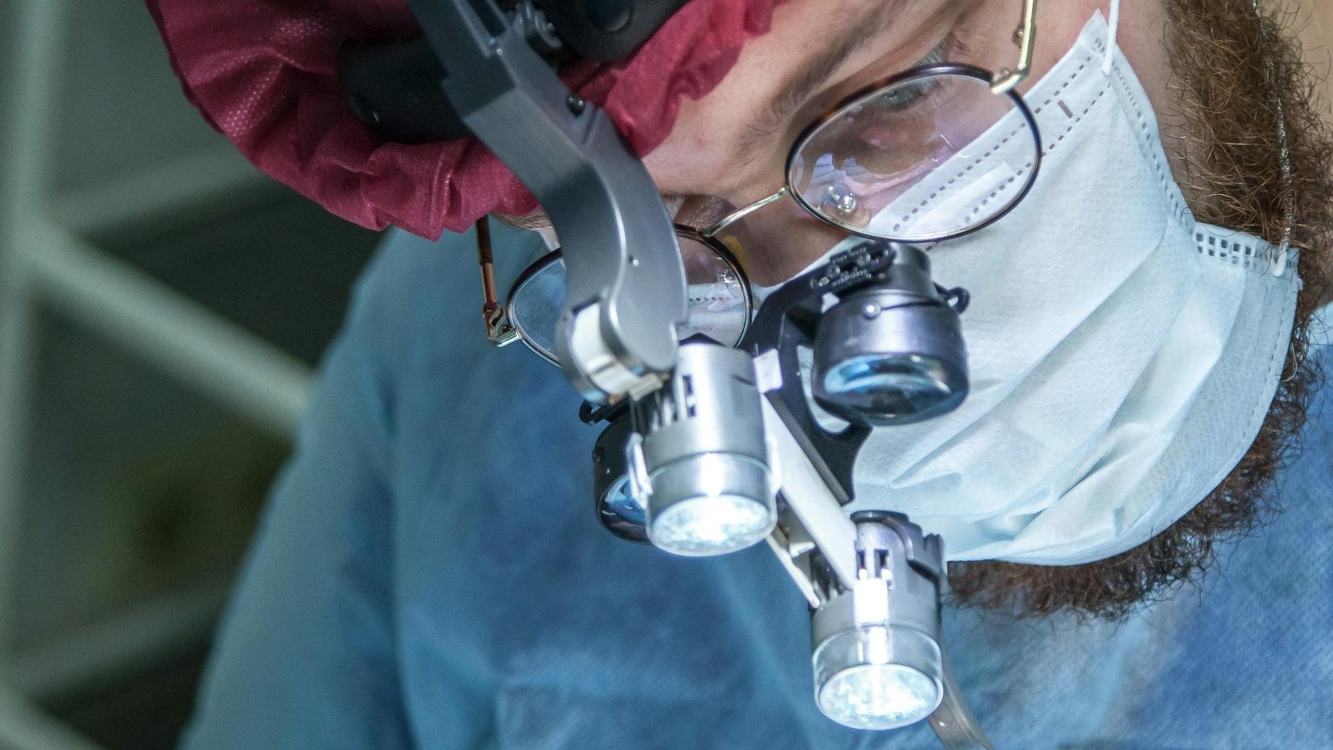 Chirurgien portant des loupes opératoires avec éclairage, la chirurgie étant le traitement de référence du ptosis