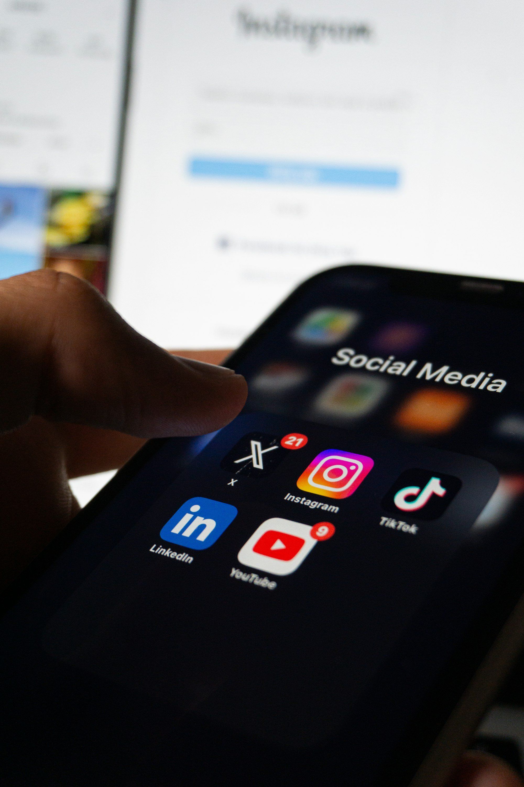 Opticienne tenant son smartphone avec les applications de réseaux sociaux visibles à l'écran, pour illustrer la présence en ligne d'une boutique d'optique