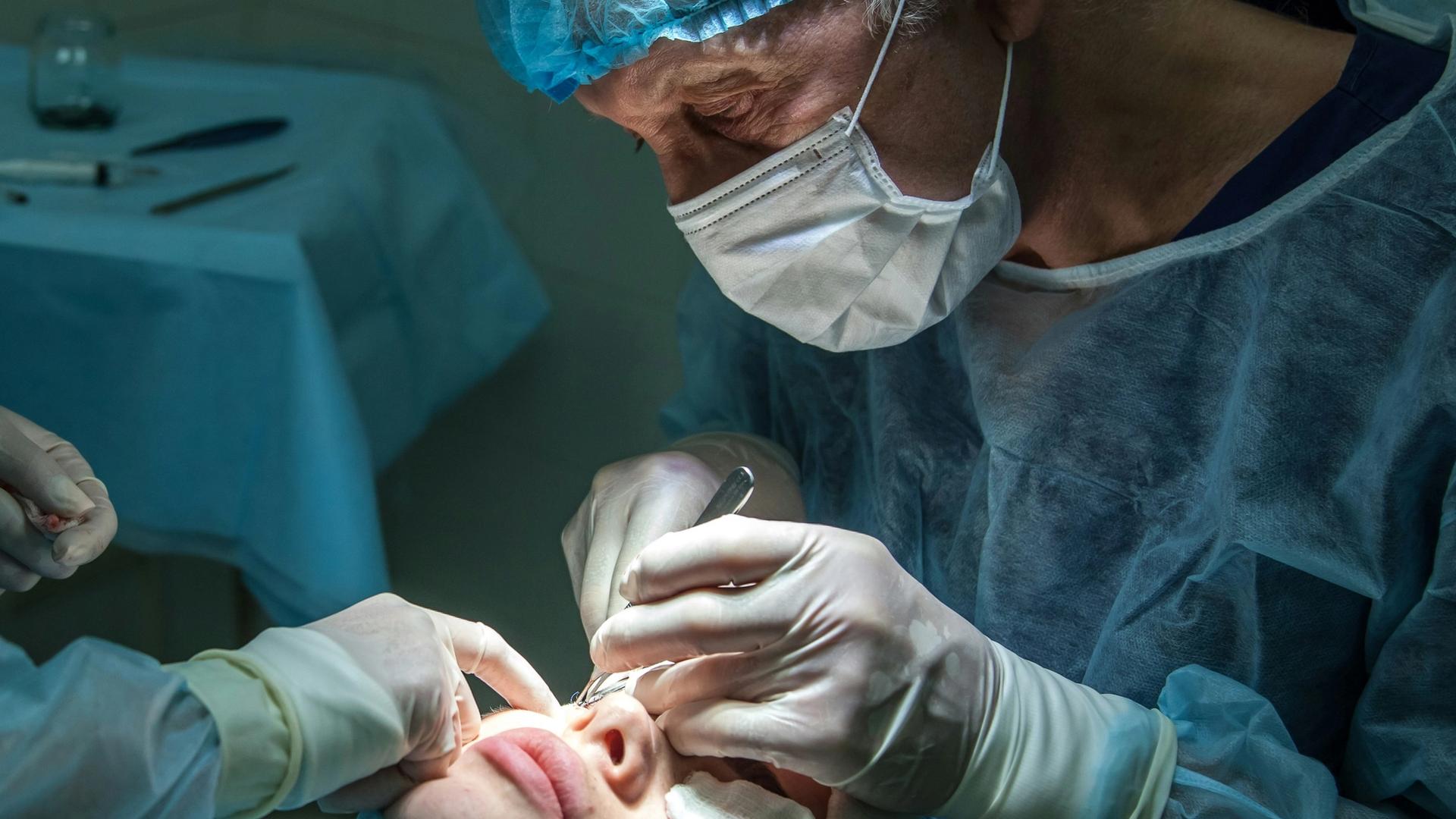 Chirurgien réalisant une intervention au laser sur un patient au bloc opératoire