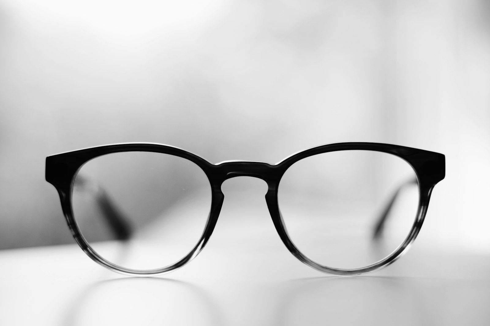 Paire de lunettes de vue noires de style wayfarer posées sur une surface blanche