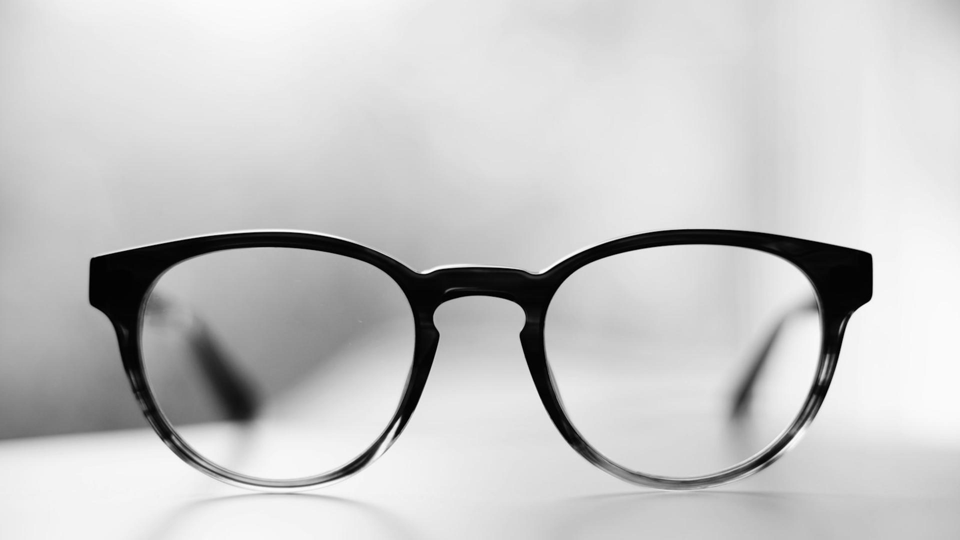 Paire de lunettes de vue noires de style wayfarer posées sur une surface blanche