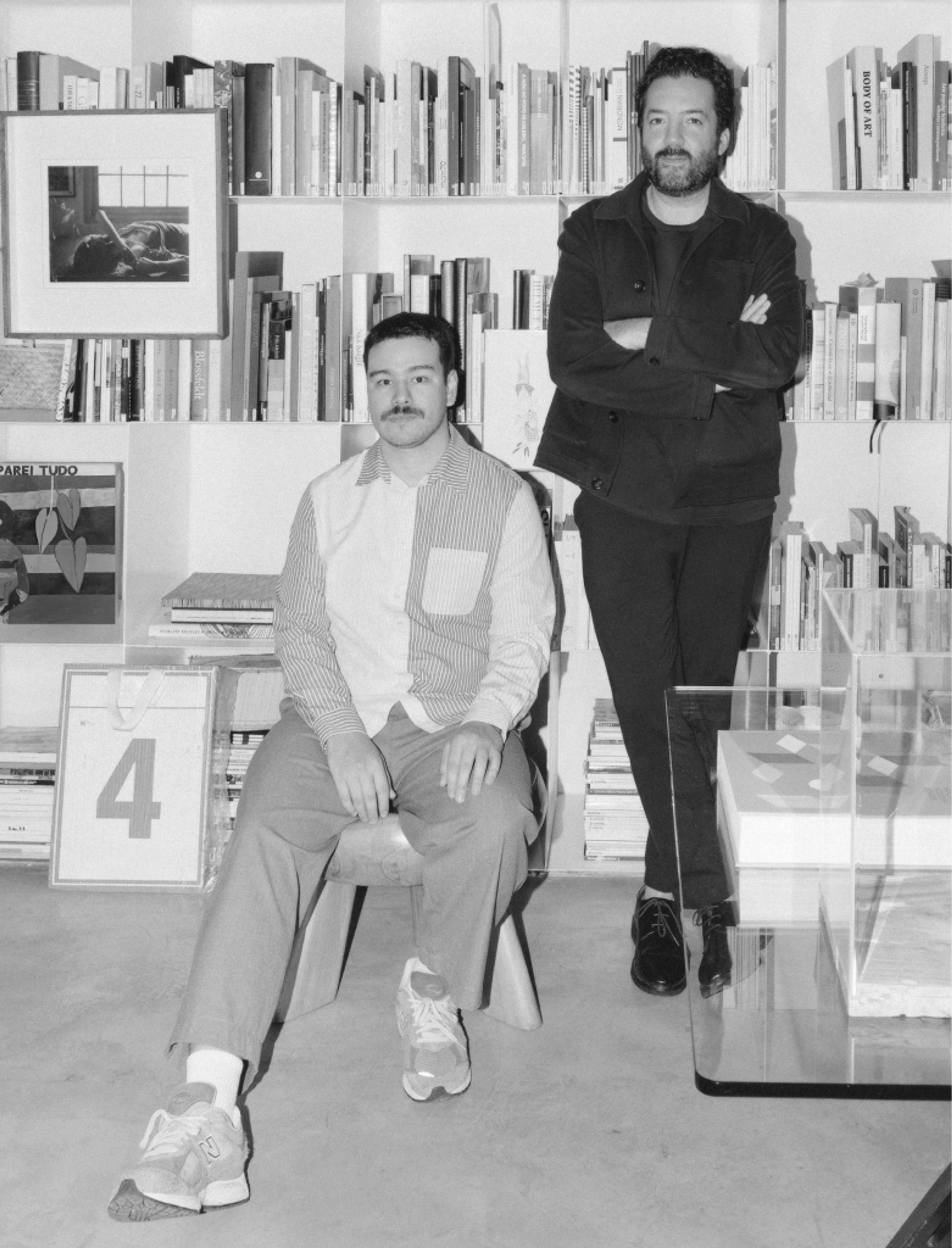 Hermes Miranda and a colleague in the TOTTTAL studio, in front of a bookshelf.