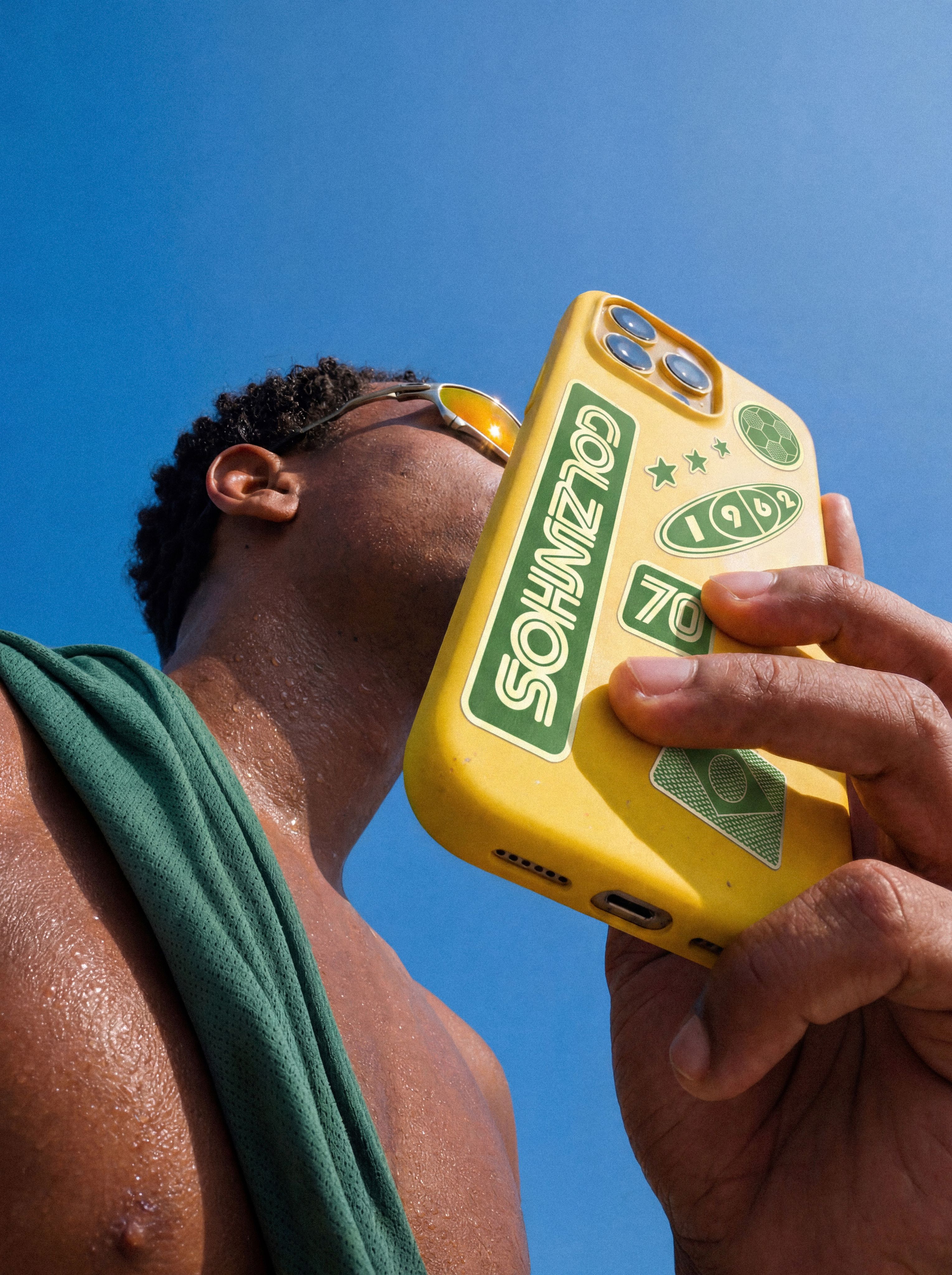 Man in sunglasses drinking from a yellow Havaianas-print can.