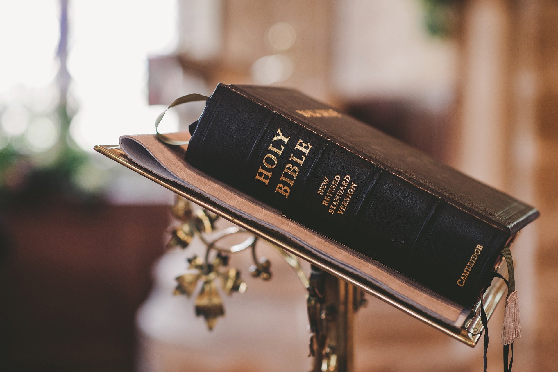 Bible noire posée sur un lutrin dans une église, éclairée par la lumière naturelle.