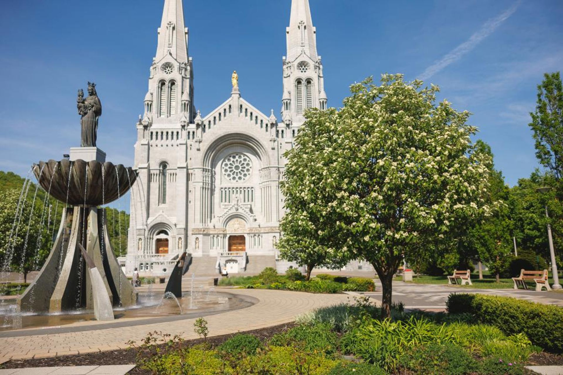 Façade de la basilique Sainte-Anne-de-Beaupré derrière un jardin et une fontaine