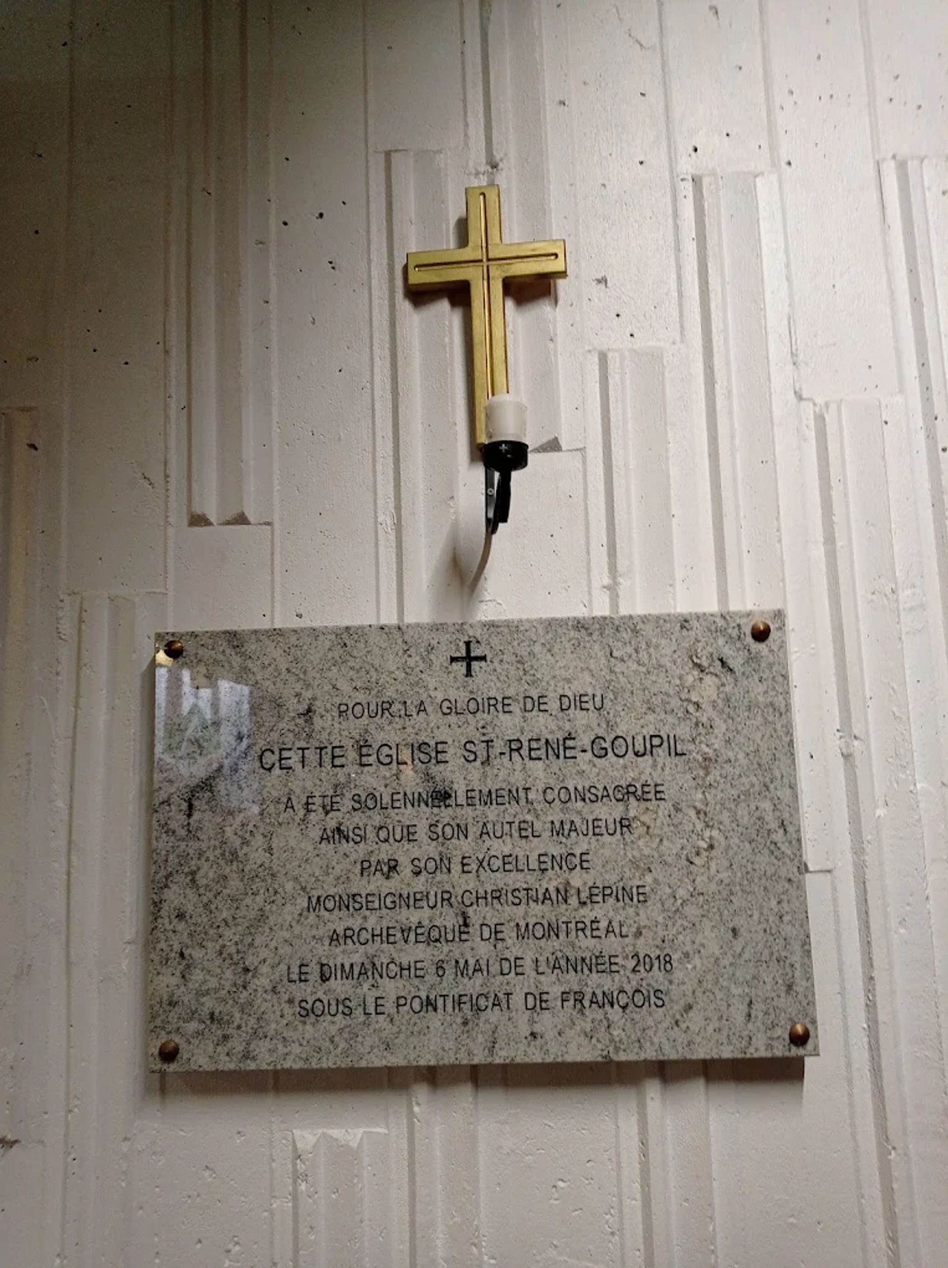 Plaque de consécration de l’église et de l’autel placée sous une croix.
