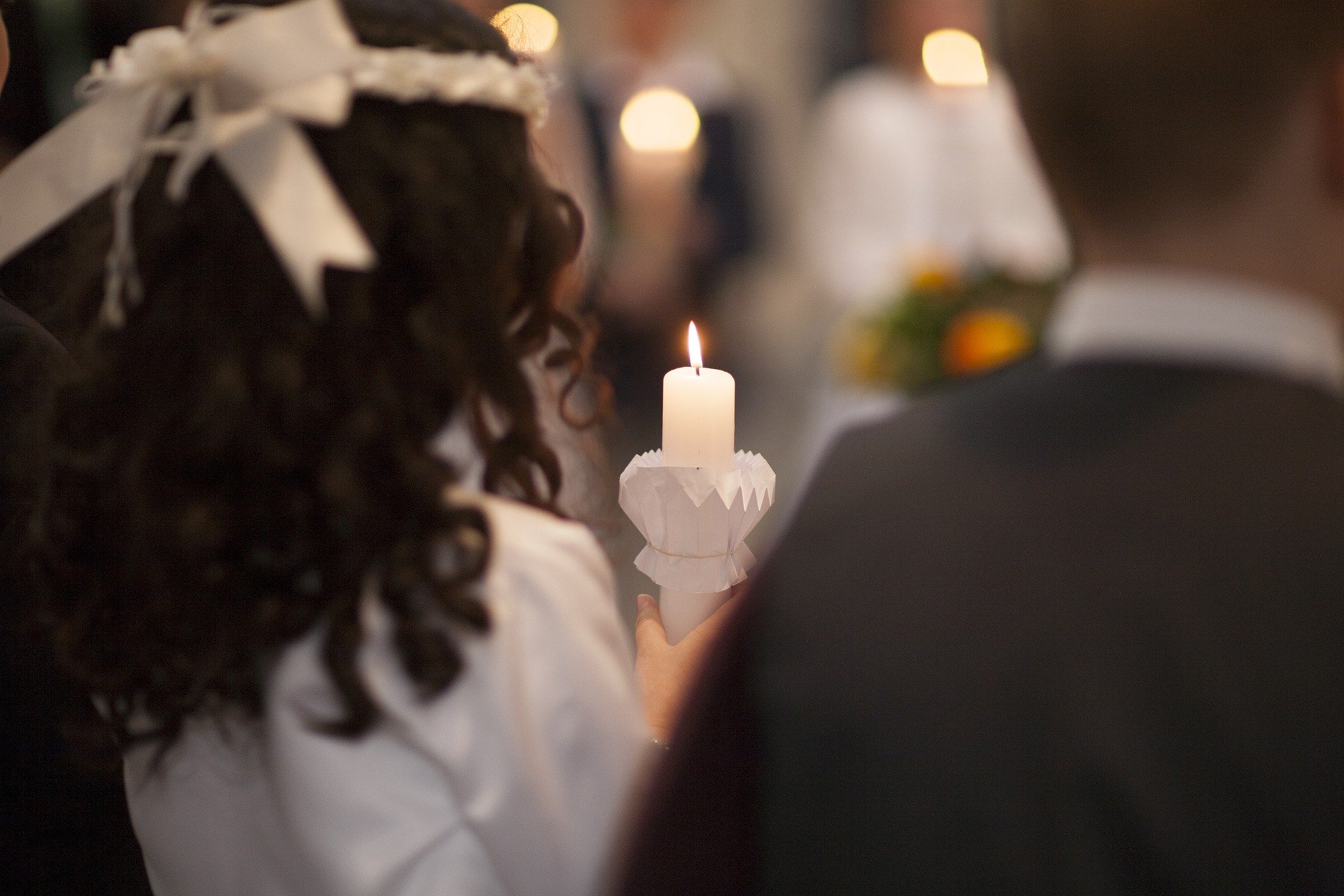 Enfant tenant un cierge lors d’une première communion; image d’illustration