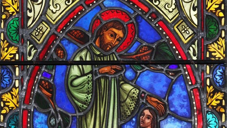 Vitrail représentant saint René Goupil, vêtu de vert, tendant la main vers une personne agenouillée