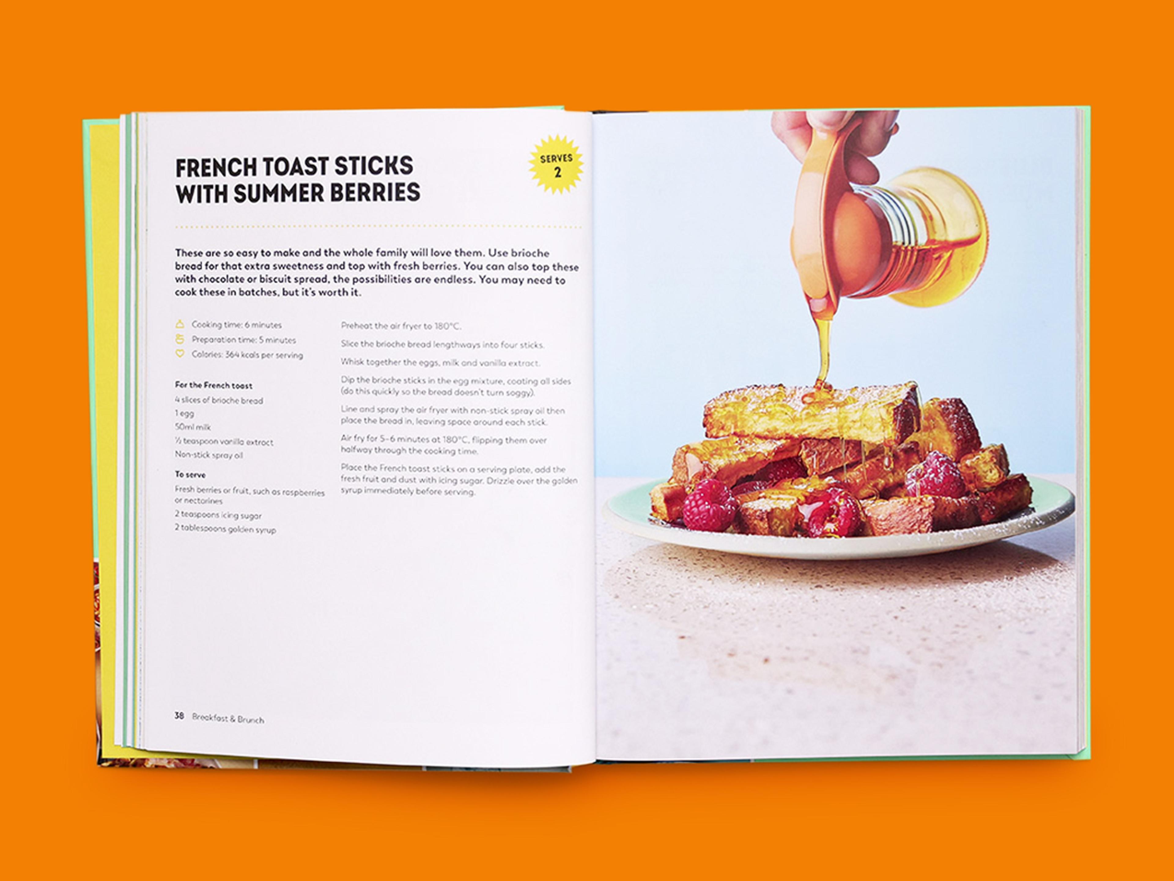 Open recipe spread titled “French Toast Sticks with Summer Berries,” showing ingredients and method on the left, and a plated stack of toast sticks with strawberries on the right, topped with syrup being poured.