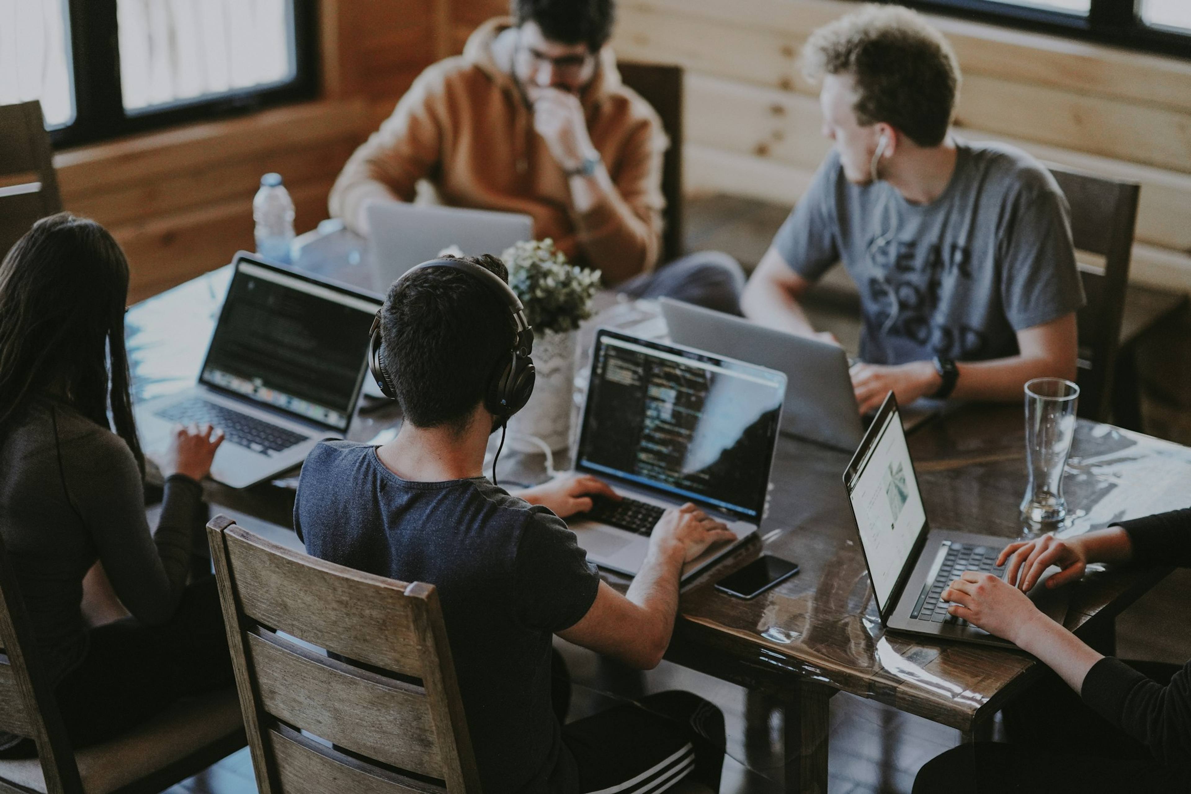 A team working together on laptops around a wooden table