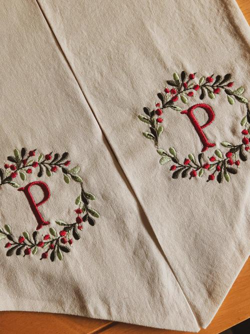 Linen napkins embroidered with a red letter "P" monogram inside a holly berry holiday wreath