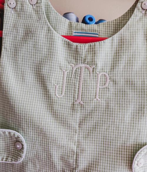 White block three-letter monogram "JMP" embroidered on the bib front of a green gingham baby romper