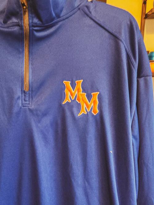 Orange and white "MM" varsity-style monogram logo embroidered on the chest of a navy quarter-zip pullover