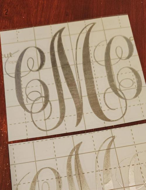 Gold script monogram heat transfer vinyl decal being cut and weeded on its carrier sheet