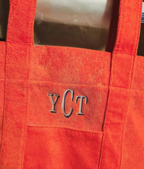 Navy and white block three-letter monogram "YCT" on an orange terrycloth beach tote bag
