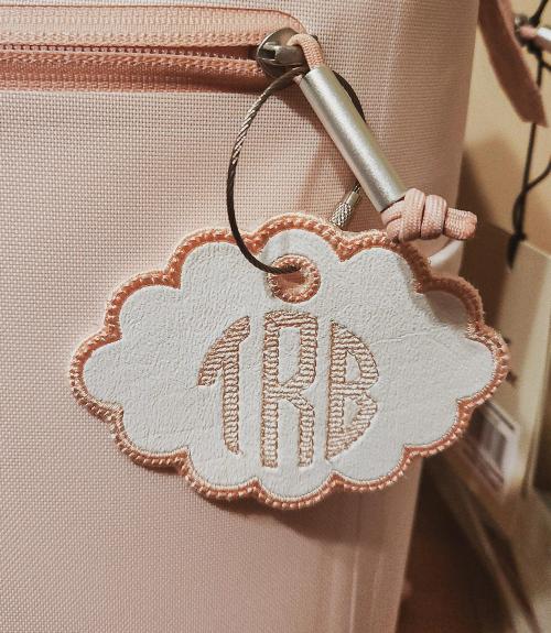 Single tan cursive script letter "M" monogram embroidered on a camel-colored terrycloth towel