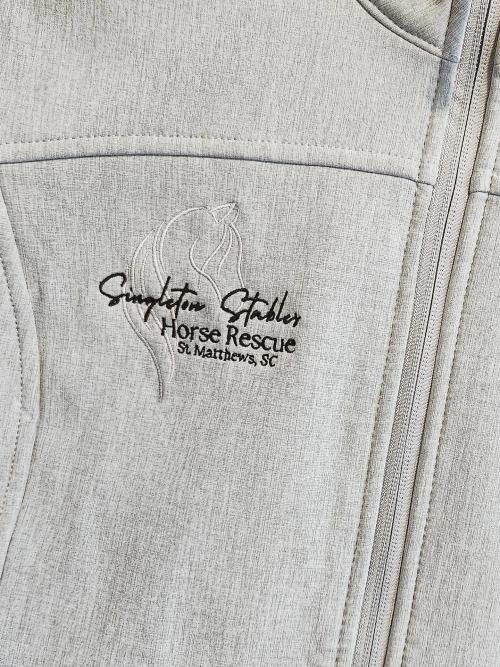 "Singleton Stables Horse Rescue, St. Matthews SC" logo with horse head icon embroidered on the chest pocket of a light gray softshell jacket