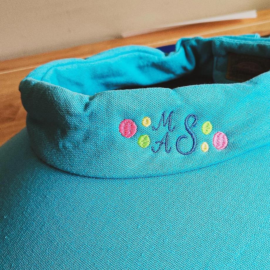 Turquoise wide-brim sun hat embroidered with a navy "MAS" monogram surrounded by colorful polka dots
