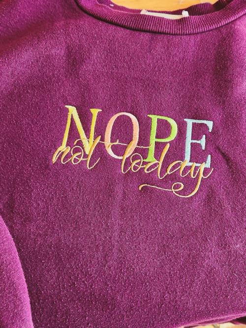 Maroon pullover sweatshirt embroidered with the playful multicolor phrase "NOPE not today"