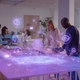 Diverse team of professionals collaborating around a futuristic holographic AI interface in a modern office, with digital icons floating above representing communication and workplace support tools