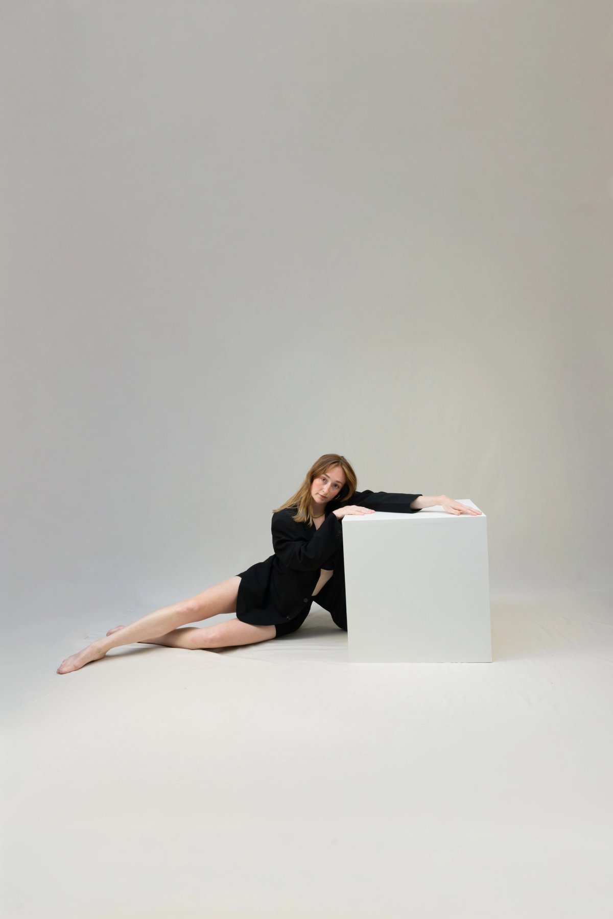 A woman posing while lying down on a posing cube 