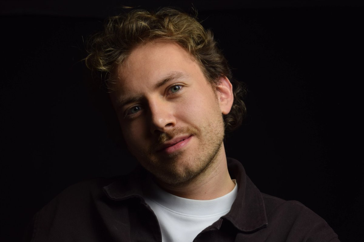 Low-key portrait of a man with curly hair lit from one side against a black background