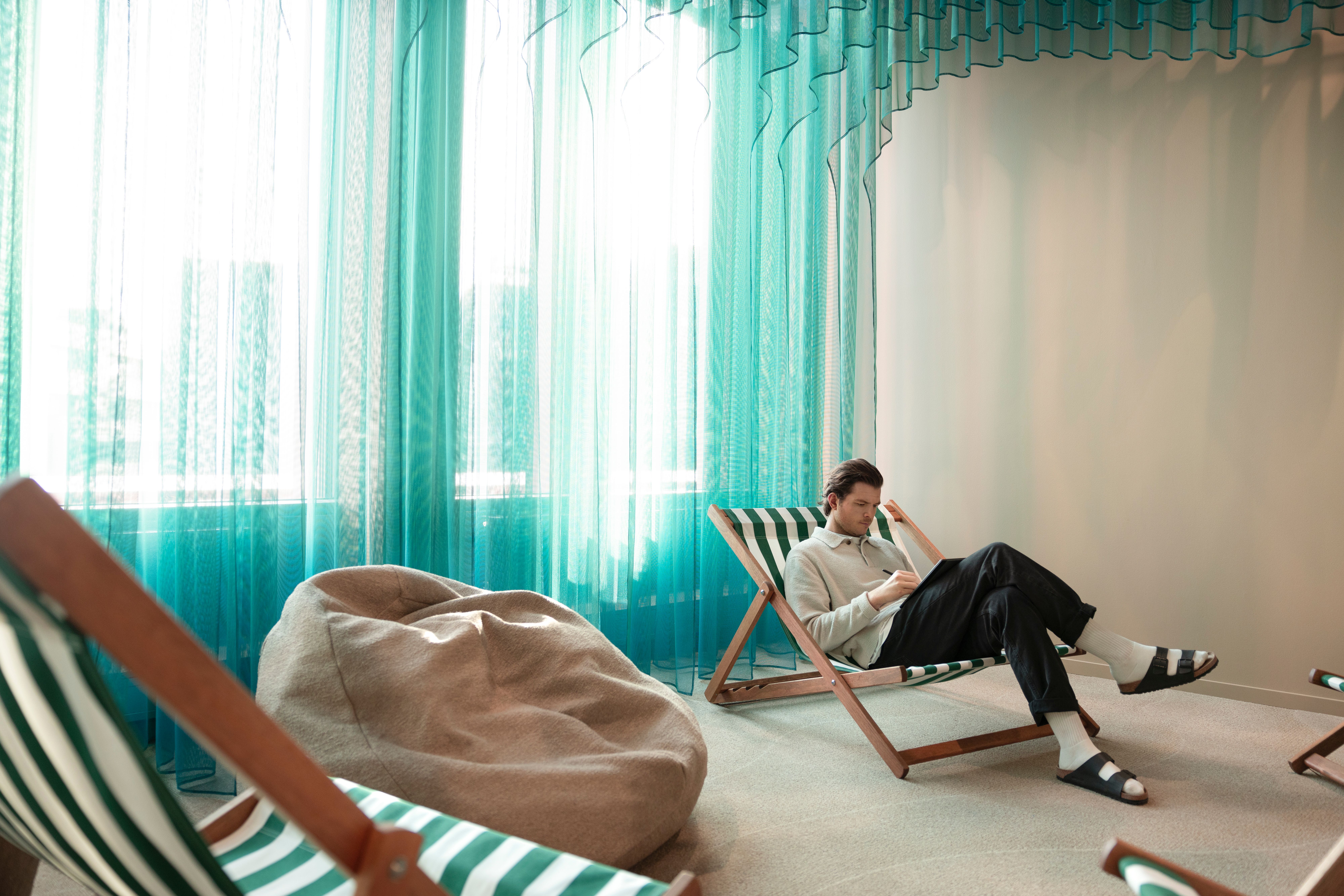 a guy sitting in a beach chair with slippers on